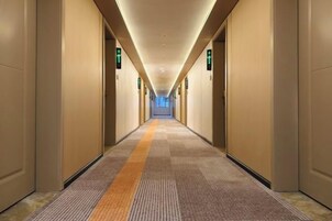 Un largo y estrecho pasillo de hotel con pisos alfombrados y puertas a ambos lados.