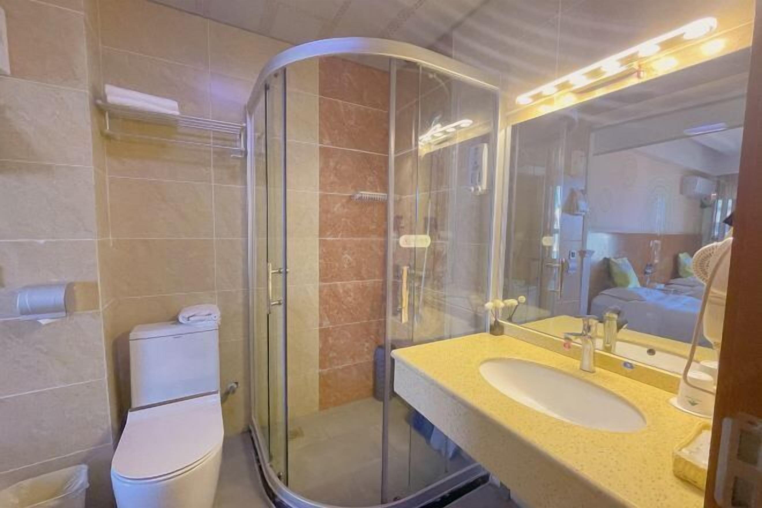 A modern bathroom with a glass-enclosed shower, a toilet, and a sink with a mirror.