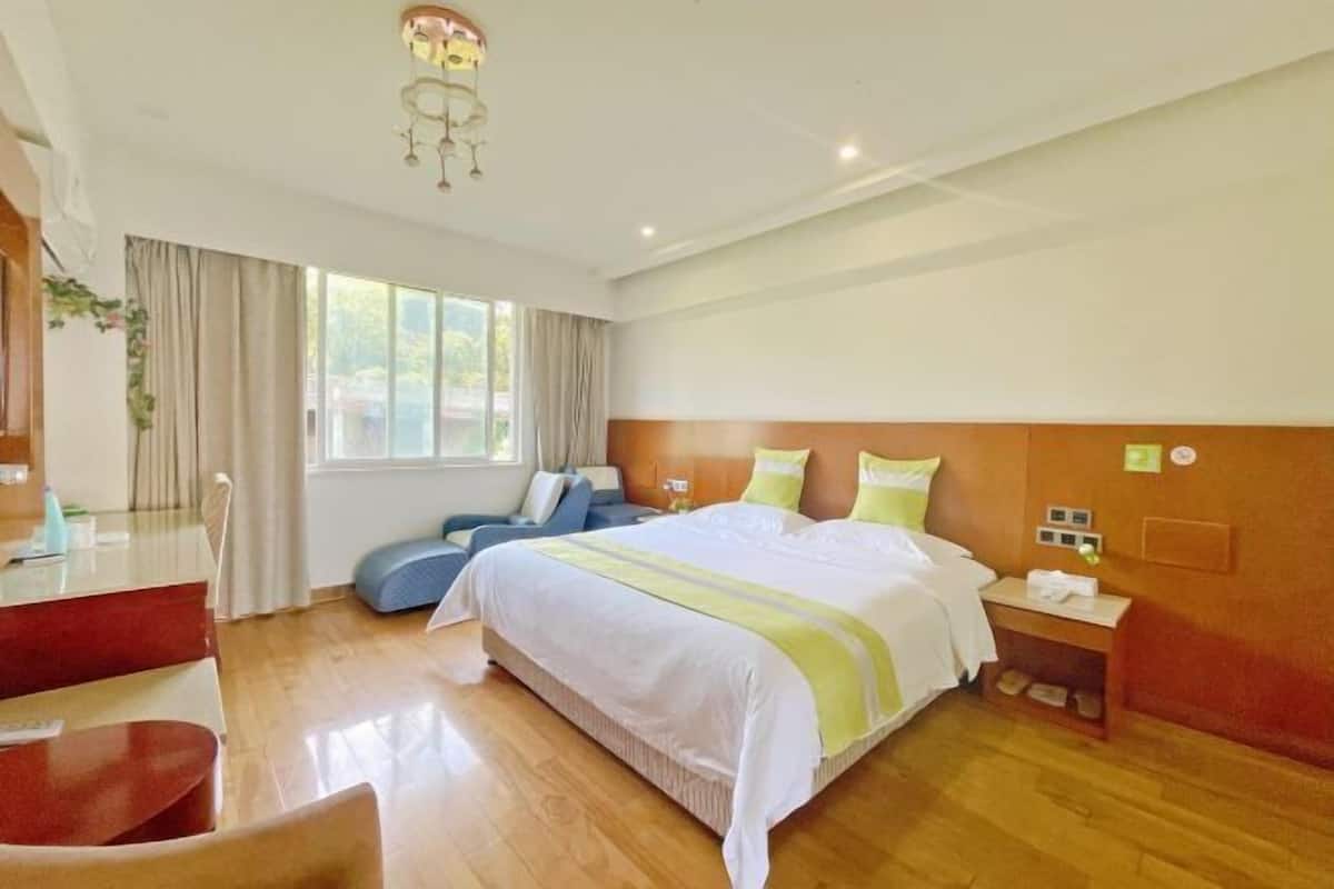 A hotel room with a large bed, a desk, and a chair.
