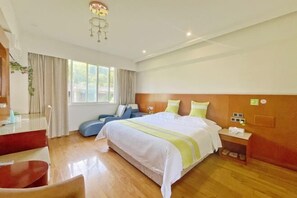 A hotel room with a large bed, a desk, and a chair.
