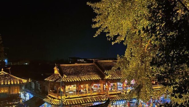 En traditionell byggnad med flera våningar och en balkong, omgiven av träd.