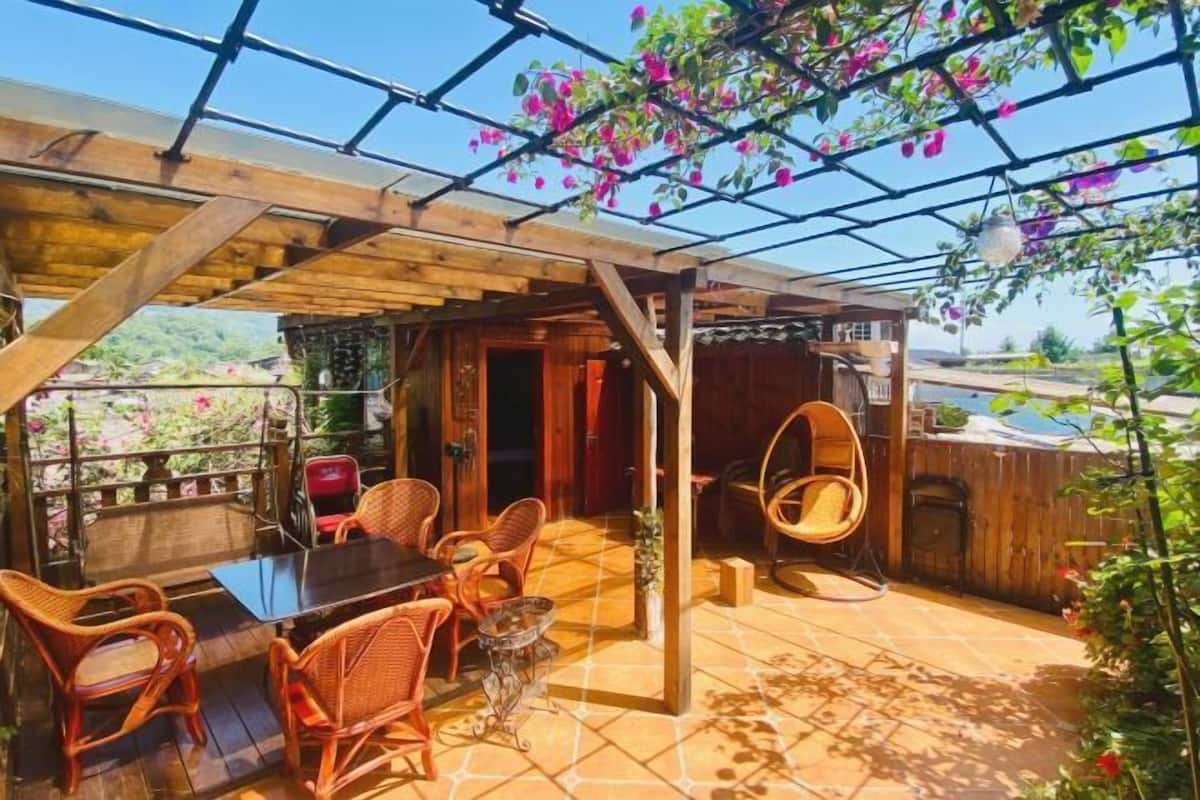 A covered patio with wicker furniture, a hanging chair, and a glass table.