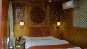 Ett hotellrum med en sänggavel i trä, en säng med vita sängkläder, två vägglampor och en dekorativ väggpanel.