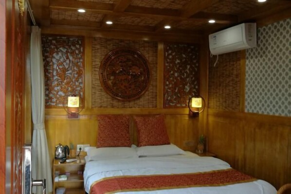 A hotel room with a wooden headboard, a bed with white bedding, two wall-mounted lamps, and a decorative wall panel.