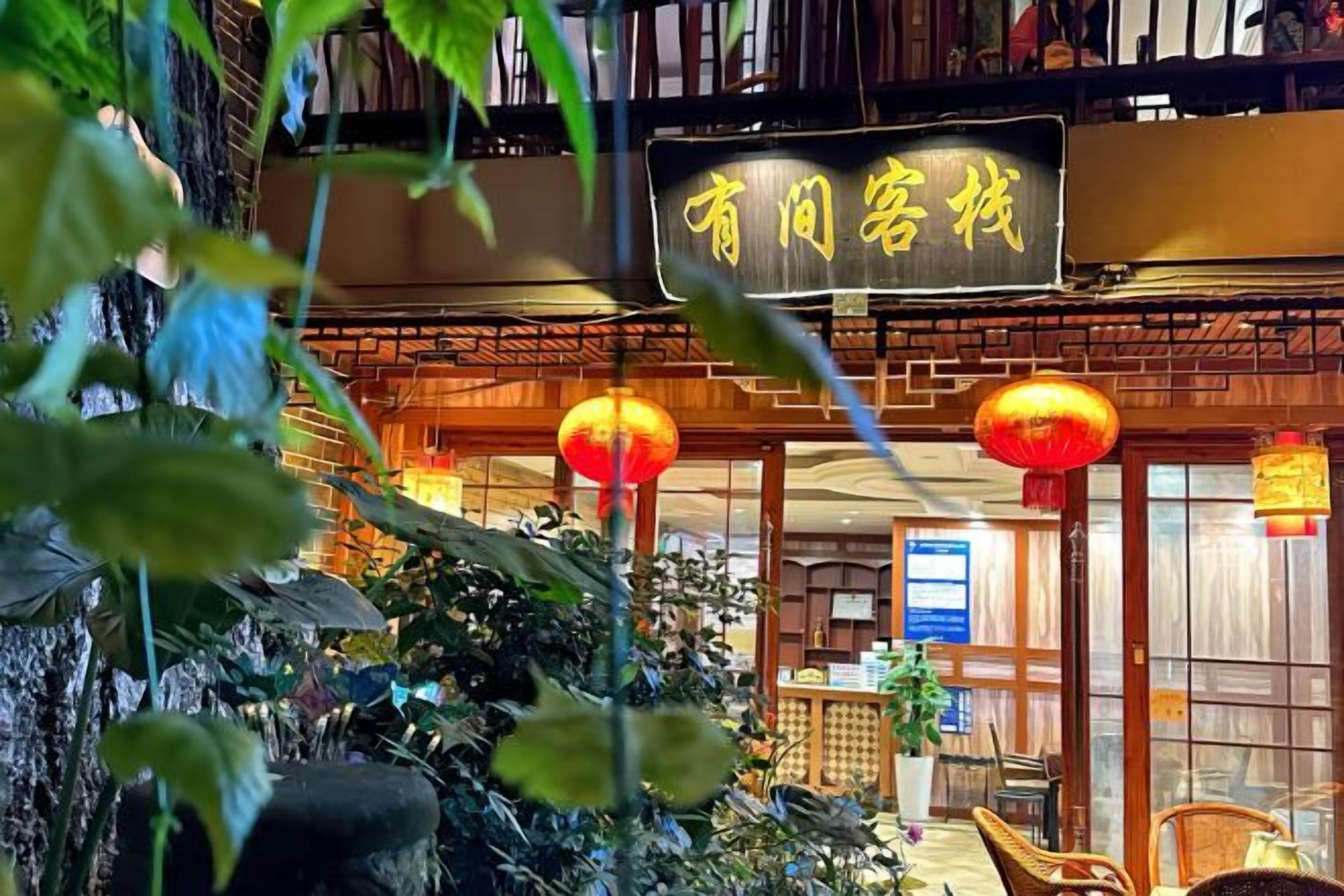 A traditional Chinese restaurant with a signboard, indoor plants, and red lanterns.