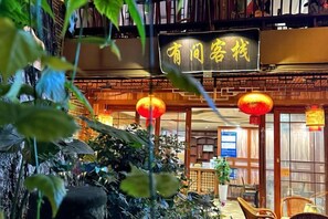 A traditional Chinese restaurant with a signboard, indoor plants, and red lanterns. - Youjian Inn (Chongzhou)