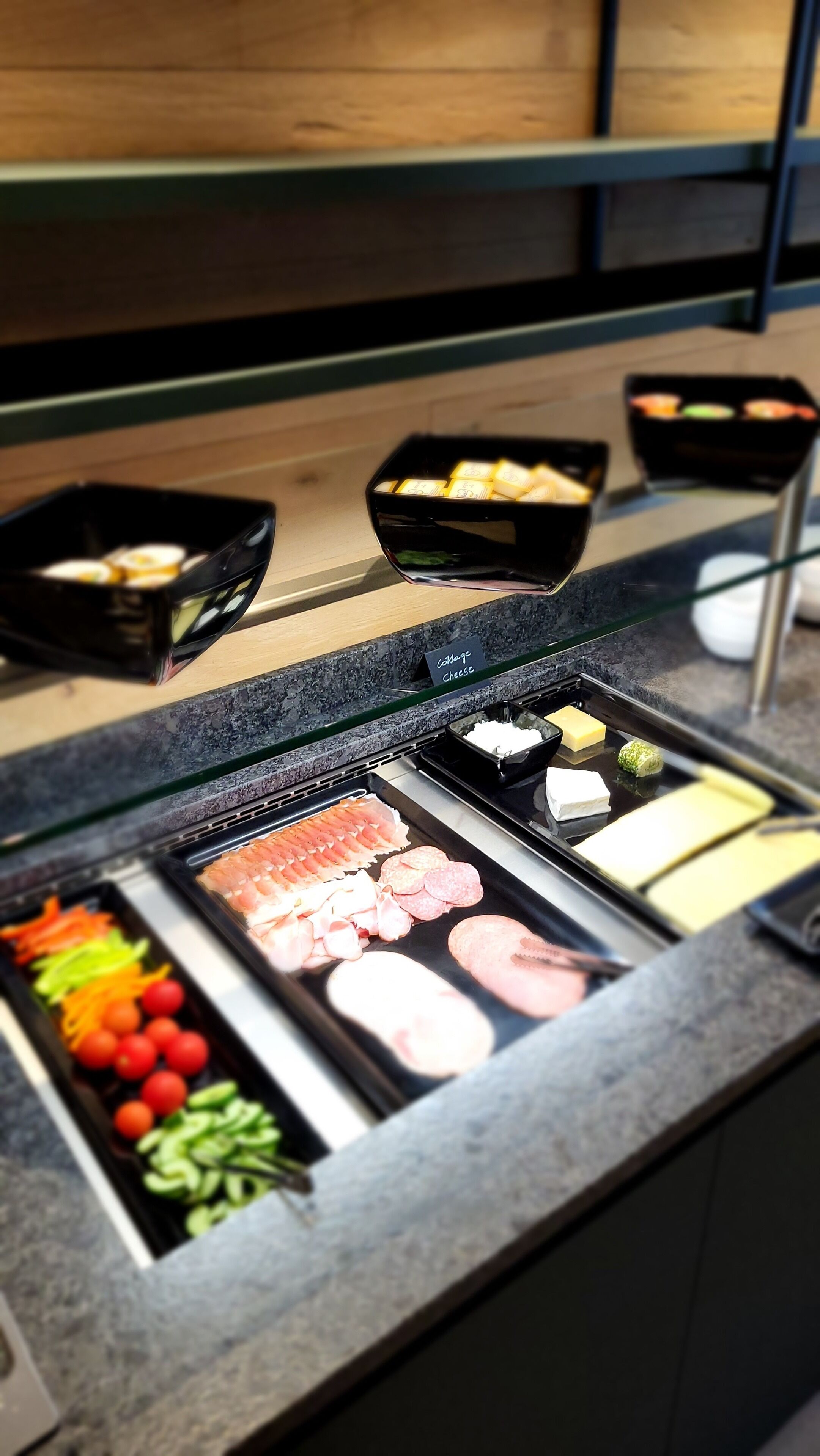 Una barra de buffet con diversos alimentos, incluyendo carnes, quesos y verduras.