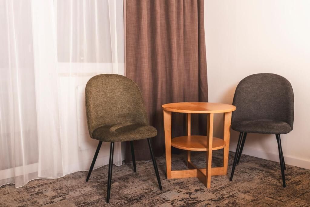 Two chairs and a small wooden table in a room with a patterned carpet.