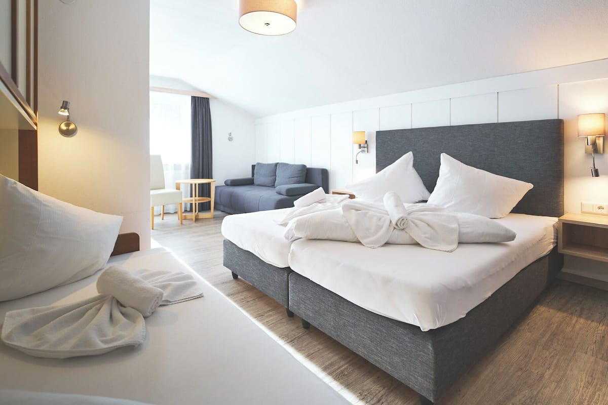 A modern hotel room with a large bed, a sofa, and a desk.