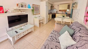Un salon avec un téléviseur, une table à manger et une cuisine en arrière-plan.