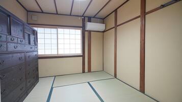Ein traditioneller japanischer Raum mit Tatami-Boden, einer Schiebetür, einem hölzernen Lowboard und einem Fenster mit Aussicht.
