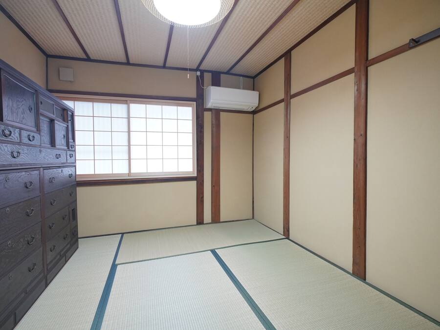 Una habitación japonesa tradicional con suelo de tatami, una puerta corredera, un aparador de madera y una ventana con vistas.
