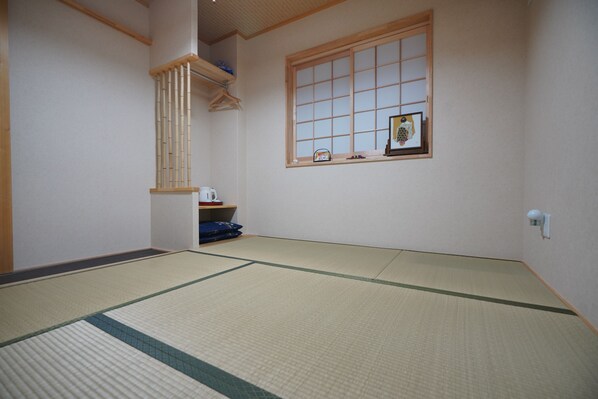 A tatami mat room with a shoji screen, a small shelf with items, and a hanging rack.