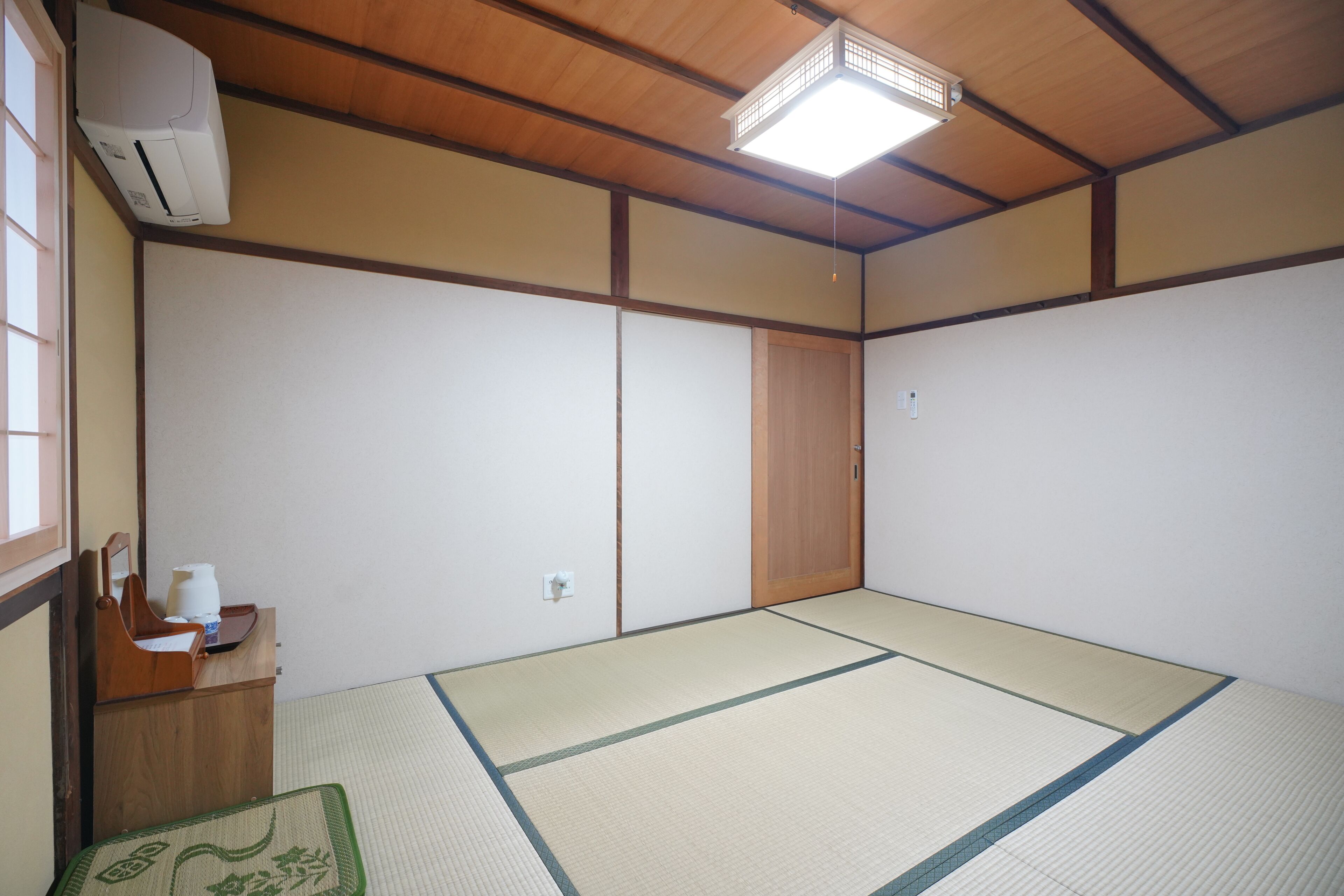Ein traditioneller japanischer Raum mit Tatami-Böden, einer Holzbalkendecke und einer verschiebbaren Tür.