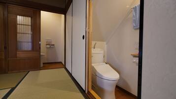 A traditional Japanese-style bathroom with a toilet, sink, and wooden sliding doors.
