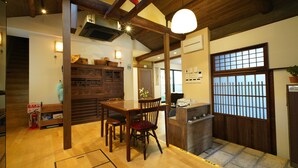 A traditional Japanese-style room with a wooden dining table, chairs, and a low wooden counter. - Uji Tea Inn (Uji)