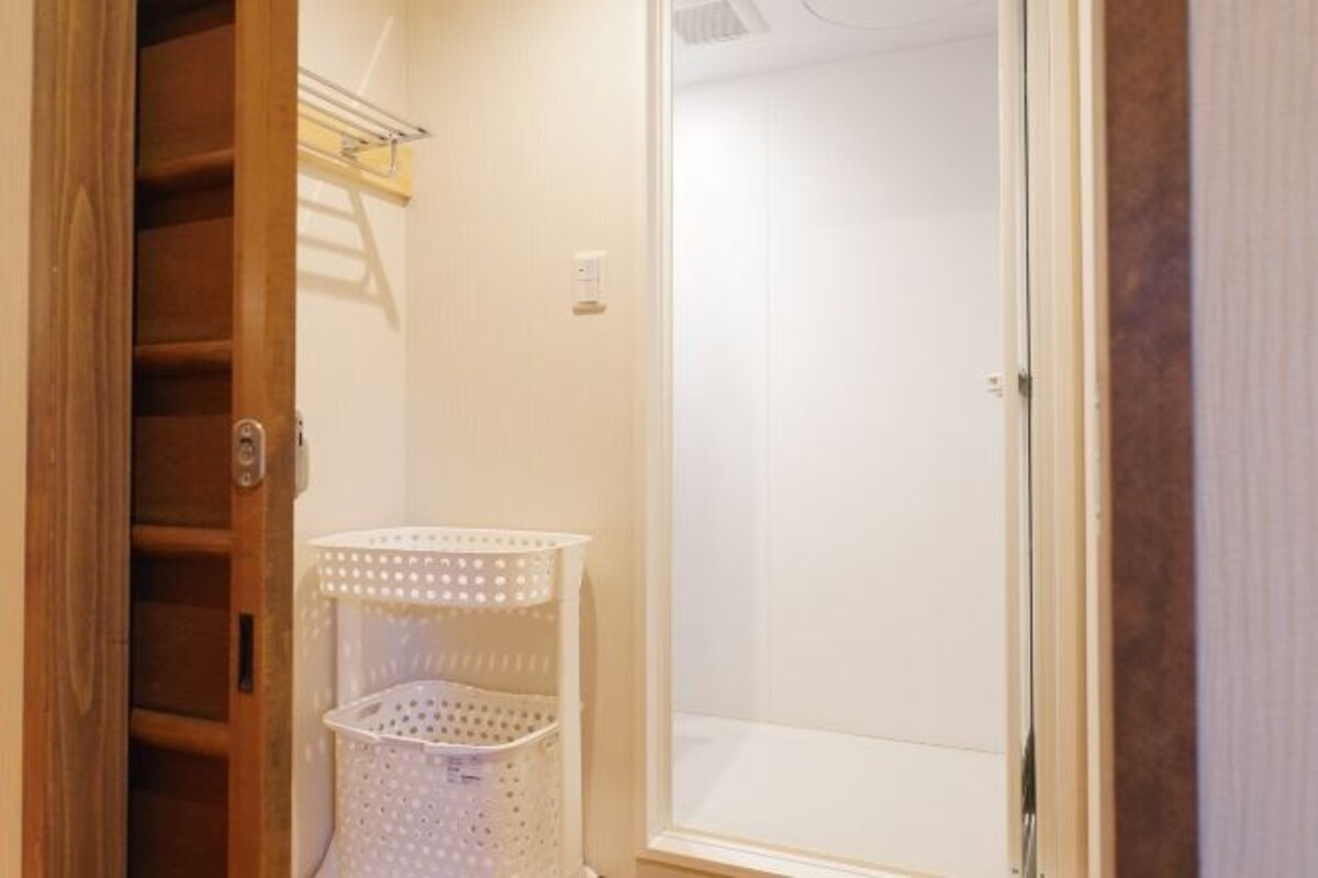 A bathroom with a wooden door, a white basket, and a window.