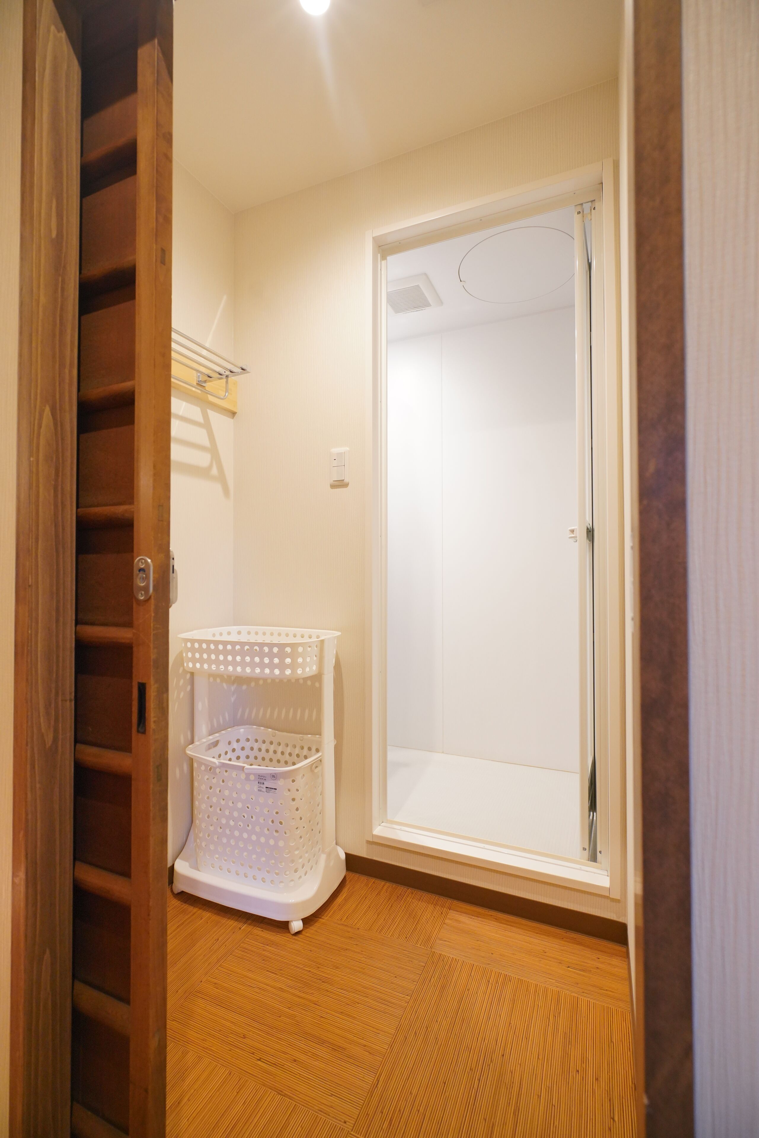 A room with a wooden floor, a white door, and a white plastic basket.
