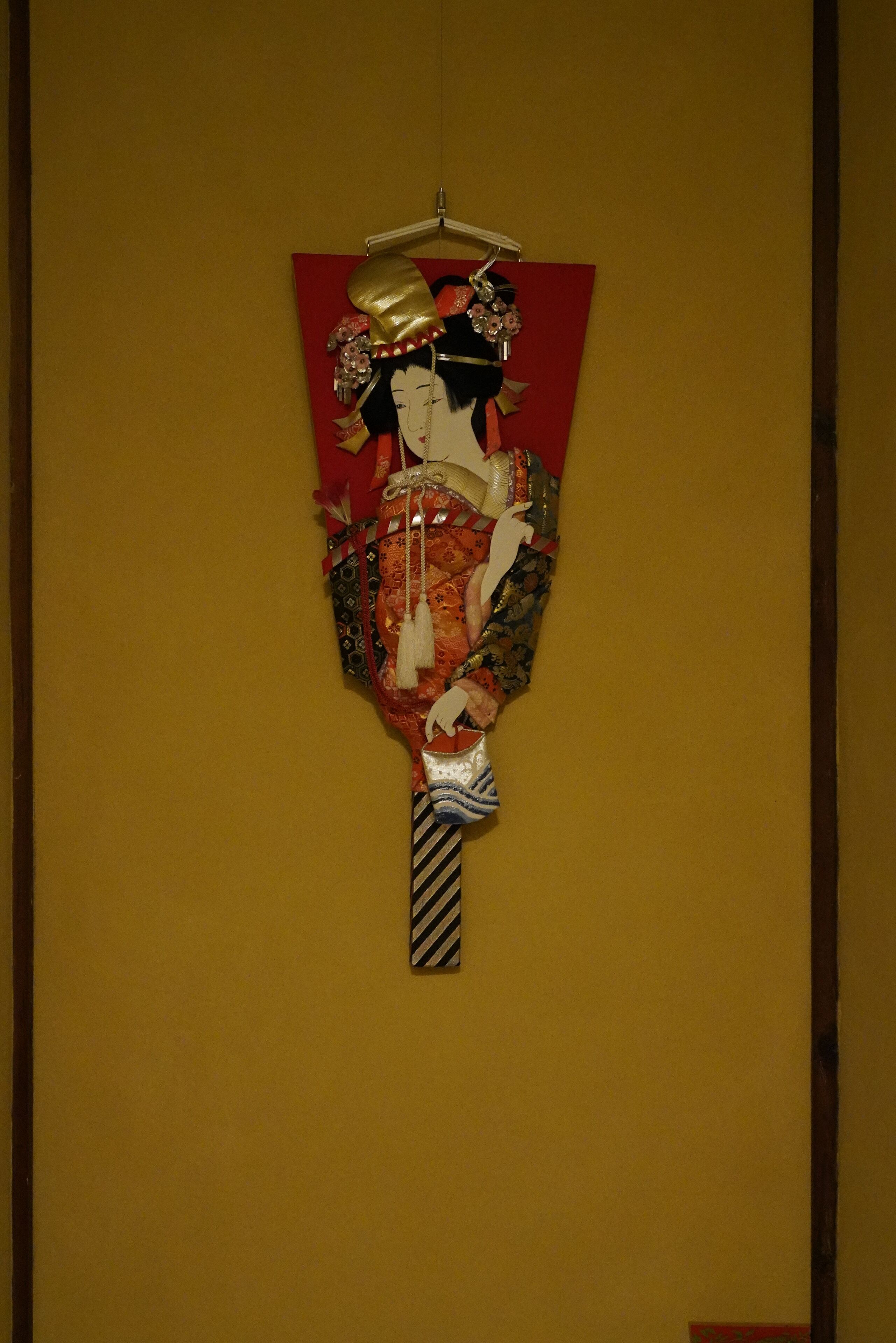 A traditional Japanese artwork on a yellow wall.