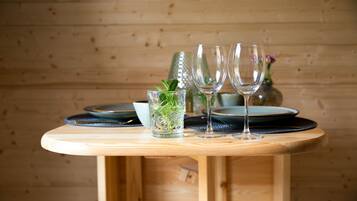Una mesa de madera con tres vasos transparentes, un vaso con hojas de menta y una botella decorativa al fondo.