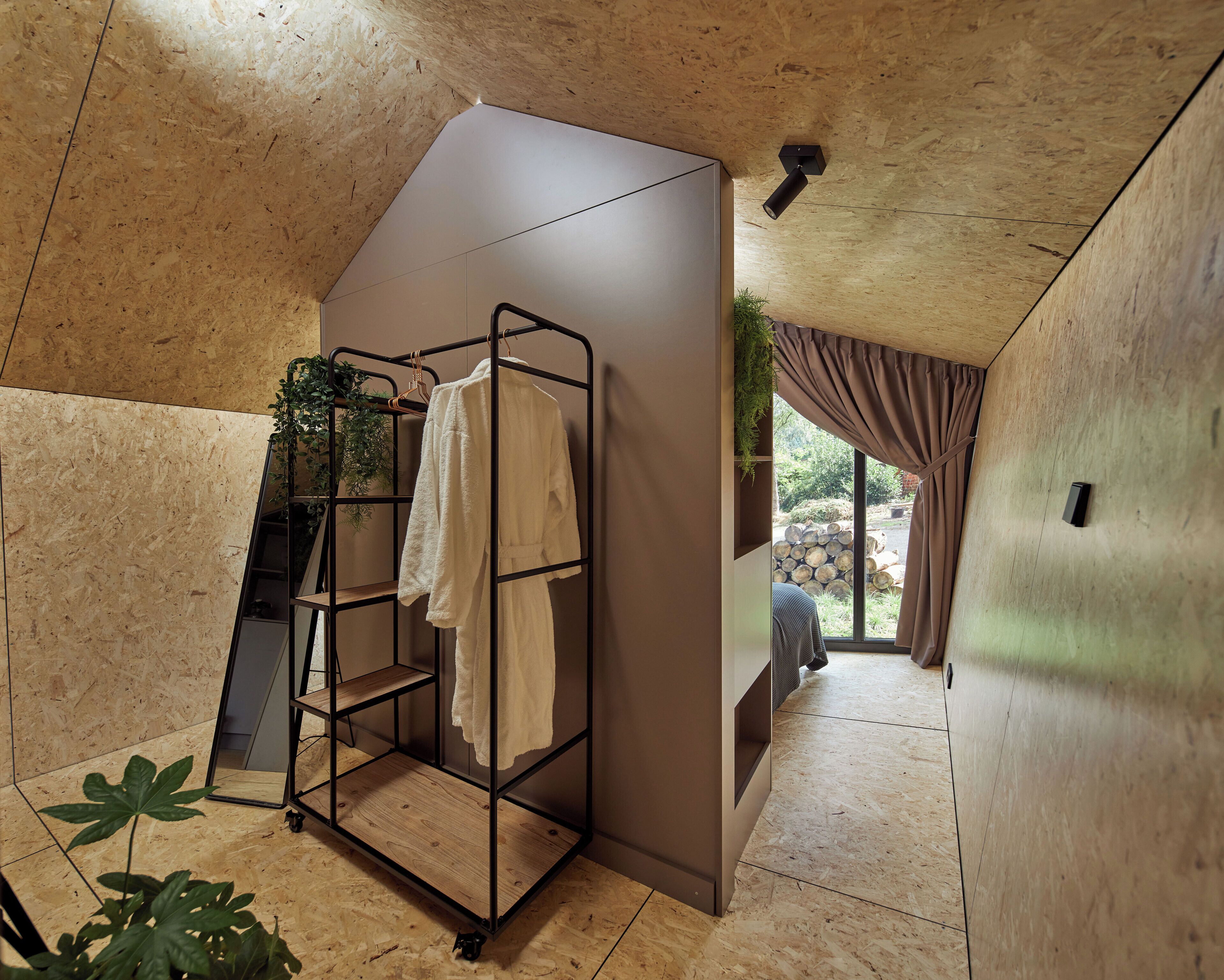 Une salle de bain moderne avec un plafond en bois, un porte-serviettes, une plante en pot et une vue sur l’extérieur.