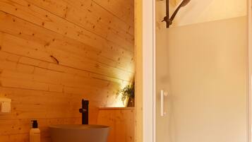 Een houten badkamer in een vakantiehuisje, met toilet, wastafel en douche.