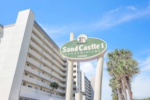 Une enseigne indiquant l’emplacement des appartements Sand Castle, avec une vue dégagée sur un immeuble de grande hauteur en arrière-plan.