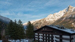 A mountain lodge with multiple balconies and a view of snow-capped mountains. - Great central location next to ski lifts and forest,spacious renovated apartment (Chamonix-Mont-Blanc)