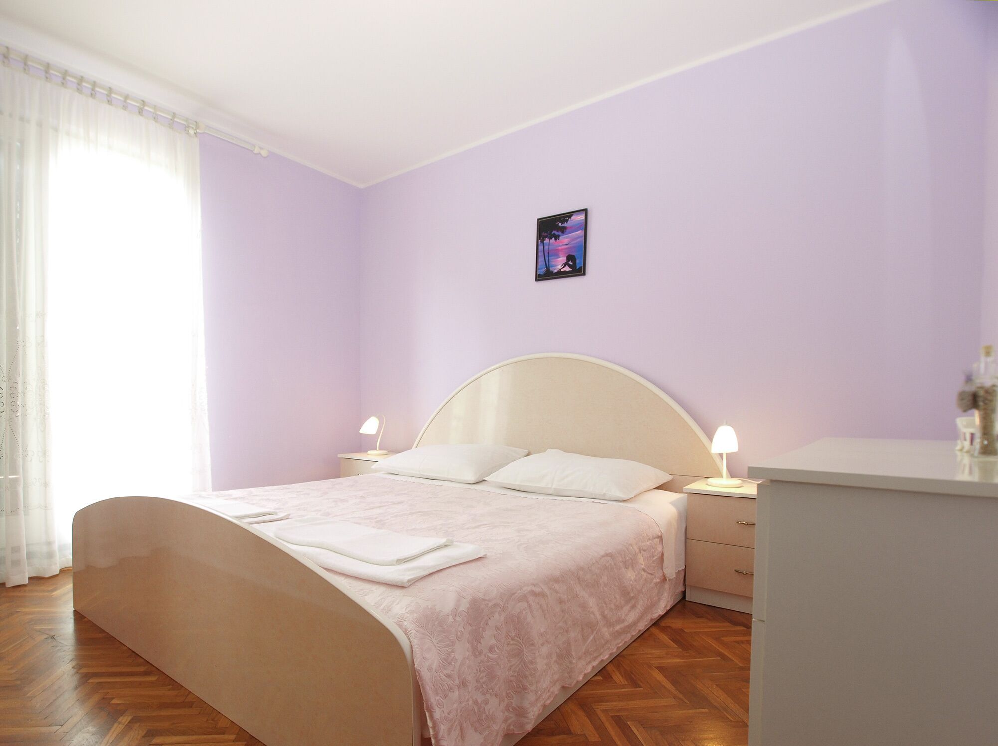 Ein Schlafzimmer mit einem Bett, zwei Nachttischen, einer Kommode und einem Wandbild.