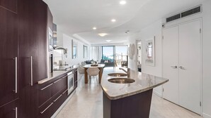 Una cocina moderna con armarios oscuros, una isla central y un comedor con vistas.