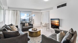 Una sala de estar moderna con un sofá, una mesa de centro y un televisor de pantalla plana montado en la pared.