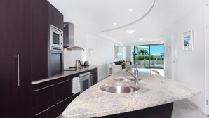 Una cocina moderna con armarios oscuros, encimera de granito y una isla grande con un fregadero.