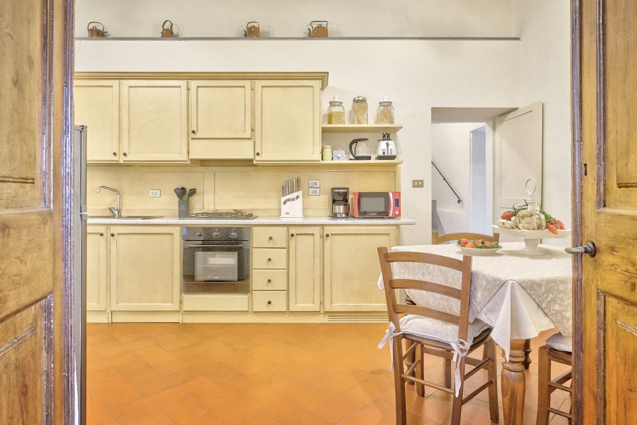 A kitchen with cabinets, a microwave, a coffee maker, and a dining table with chairs.