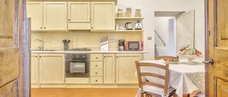 A kitchen with cabinets, a microwave, a coffee maker, and a dining table with chairs.