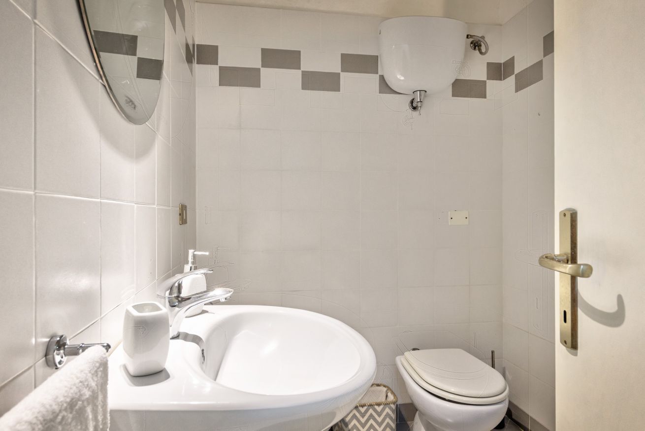 A bathroom with a sink, toilet, and mirror.