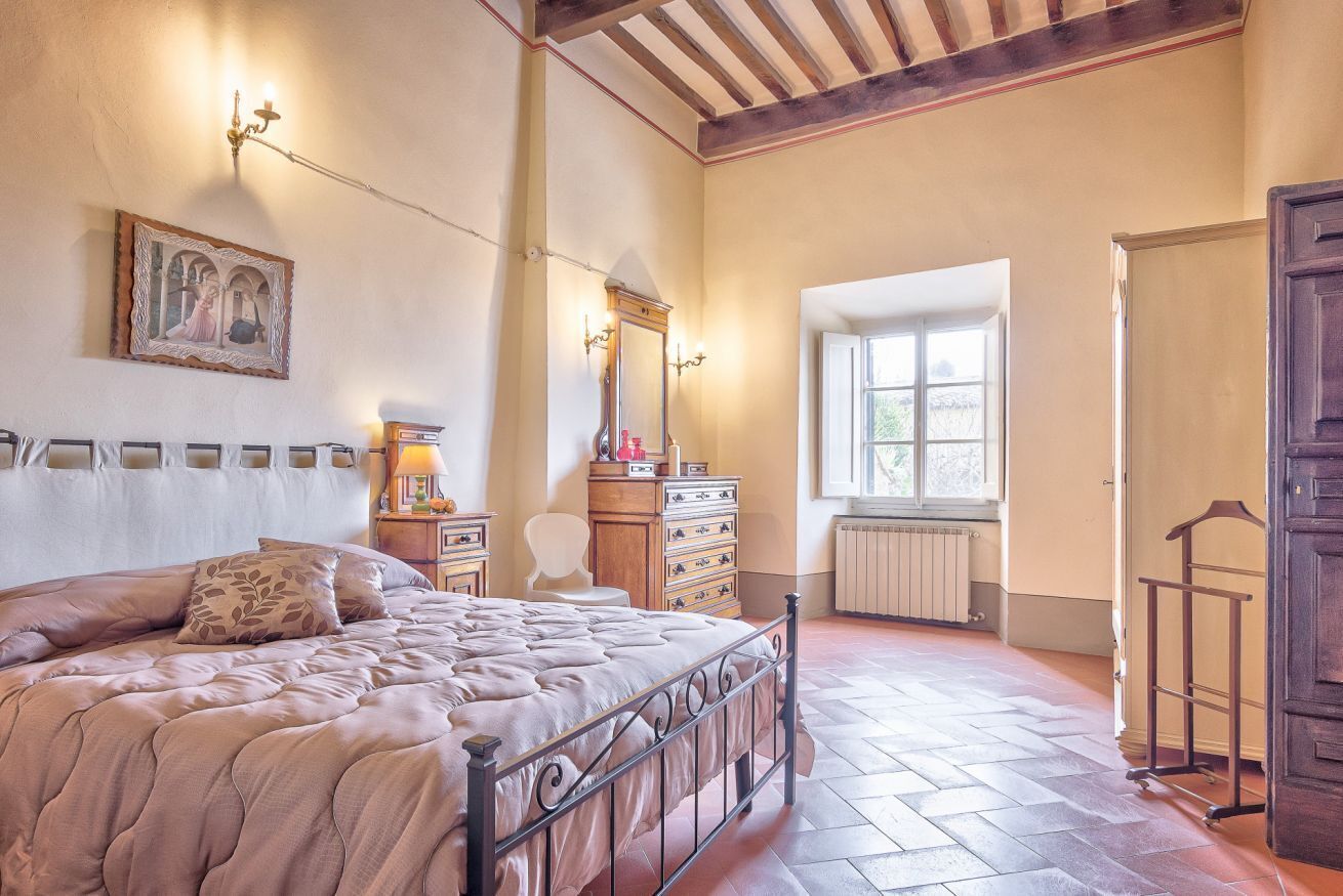 Una camera da letto con un letto, una cassettiera, uno specchio e una finestra.
