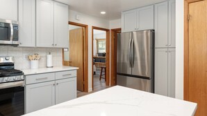 A modern kitchen with white cabinets, stainless steel appliances, and a marble countertop.