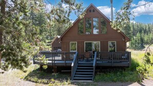 A cabin with a deck, outdoor seating, and a chimney.