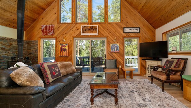 A cozy living room with a high ceiling, a fireplace, a leather sofa, a coffee table, and a television.