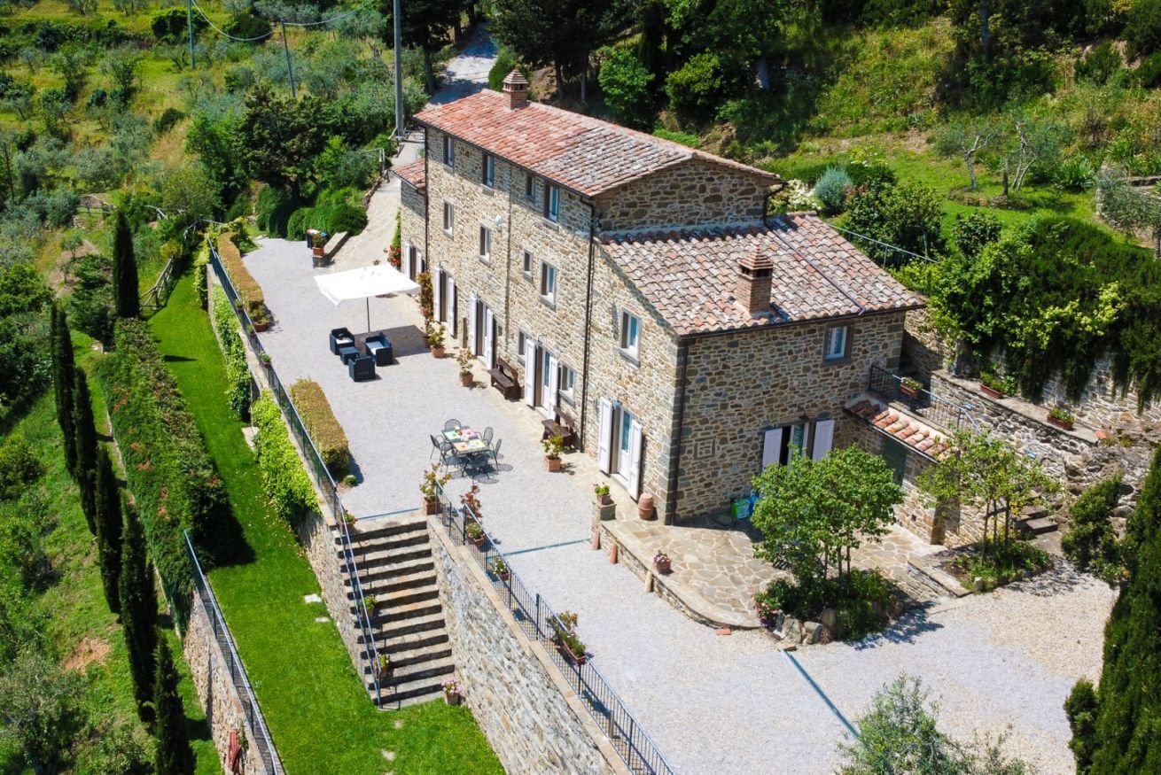 A stone building with a tiled roof, a paved driveway, and a small garden area.