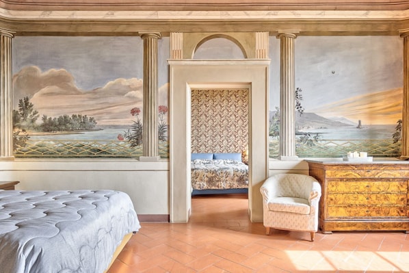 A bedroom with a bed, a chair, a dresser, and a mural on the wall.