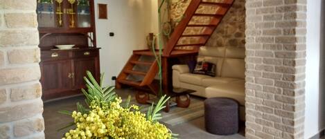 A living room with a stone fireplace, a wooden staircase, and a sofa.