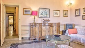 Una habitación con un armario de madera, una mesa redonda, un sofá y cuadros en la pared.