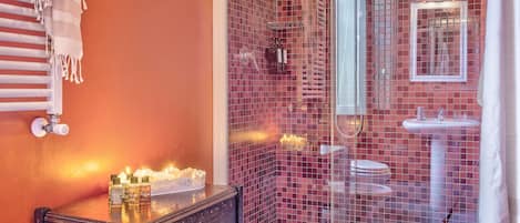 A bathroom with a glass shower enclosure, a white bathtub, a sink, and a mirror.