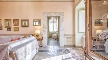Una camera d'albergo con un letto, uno specchio, una porta che dà su un'altra stanza e un corridoio con pavimento in marmo.