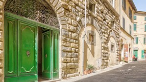 Ein Steinhaus mit grünen Türen, einem verzierten Bogen und einer schmalen Gasse.