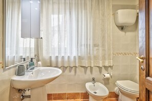 Une salle de bain équipée d’un lavabo, d’un bidet, de toilettes et d’un miroir.