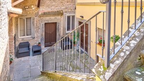 A narrow staircase leading to a stone building with a wooden door and a window. - La Terrazza - apartment with breathtaking view (Cortona)