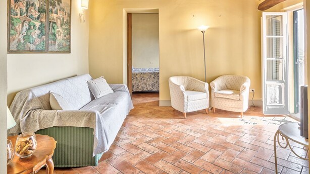 A room with a sofa, two armchairs, a floor lamp, a painting, and a tiled floor. - La Terrazza - apartment with breathtaking view (Cortona)