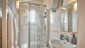 A bathroom with a glass-enclosed shower, a white toilet, and a sink with a mirror above it. - La Terrazza - apartment with breathtaking view (Cortona)